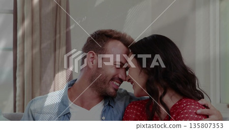 Smiling couple leaning with foreheads touching on sofa in living room, with curtains, window frame Smiling couple leaning with foreheads touching on sofa in living room, with curtains, window frame 135807353