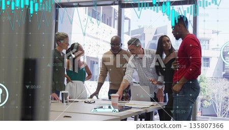 Discussing six colleagues reviewing printed charts in conference room, with laptop and coffee Discussing six colleagues reviewing printed charts in conference room, with laptop and coffee 135807366