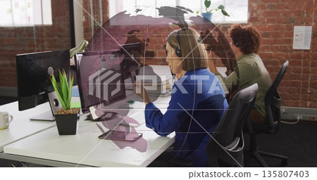Answering support queries woman wearing blue blazer and headset in loft office, with globe overlay Answering support queries woman wearing blue blazer and headset in loft office, with globe overlay 135807403