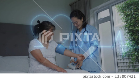 Nurse wearing blue scrubs wrapping blood pressure cuff around patient arm in bedroom 135807421