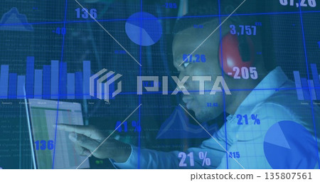 Pointing adult man wearing red headphones viewing financial charts on laptop in office, copy space Pointing adult man wearing red headphones viewing financial charts on laptop in office, copy space 135807561