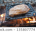 戶外露營的烹飪場景,人們在營火上烤肉。 戶外露營的烹飪場景,人們在營火上烤肉。 135807774