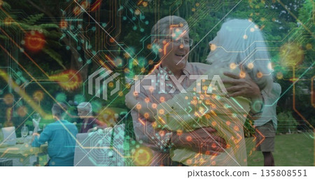 Dancing senior couple swaying on backyard lawn, with wine glasses on small table and tech overlay Dancing senior couple swaying on backyard lawn, with wine glasses on small table and tech overlay 135808551
