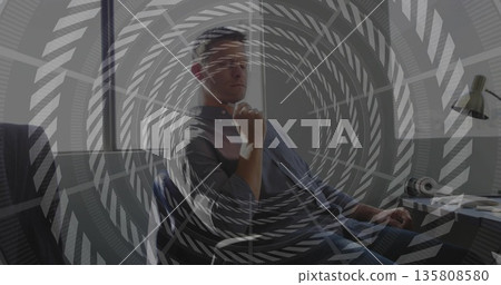 Leaning man wearing button-down shirt and jeans at office window, with desk lamp headphones 135808580