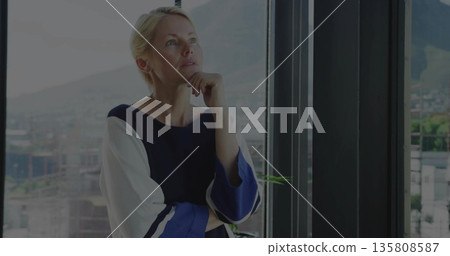 Standing woman in blouse gazing over cityscape from highrise window with potted plant, copy space 135808587
