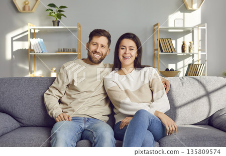 Portrait of a happy, smiling family couple sitting on the sofa in the living room Portrait of a happy, smiling family couple sitting on the sofa in the living room 135809574