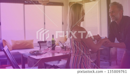 Holding hands couple standing by porch dining table, with wine glasses and lantern, copy space 135809761