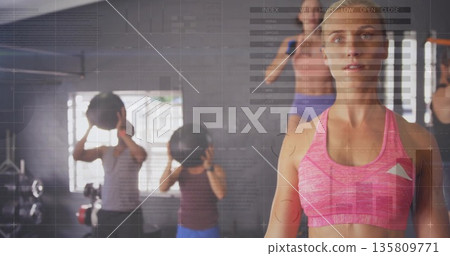 Trainer in sportswear guiding group using medicine balls in gym, with data overlays, copy space Trainer in sportswear guiding group using medicine balls in gym, with data overlays, copy space 135809771