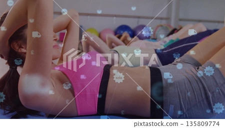 Five women doing crunches in gym, with mats, balls near mirrored wall, digital overlay icons Five women doing crunches in gym, with mats, balls near mirrored wall, digital overlay icons 135809774