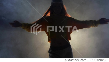Striking dancer holding arms out on stage, with cap cropped hoodie sweatpants spotlight fog effect 135809852