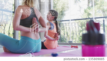 Holding reversed prayer pose mom and daughter practicing yoga at home, with mask notification icons 135809885