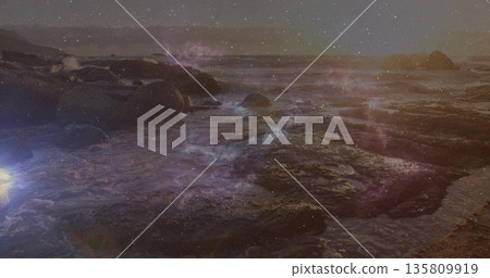 Glowing rocky tidal pools, shallow water and boulders reflecting cosmic star overlay at shoreline 135809919