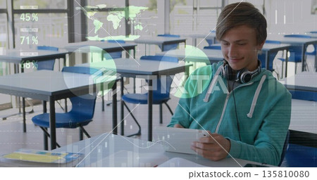 Holding tablet viewing data overlays teen in green hoodie in classroom, with headphones, copy space Holding tablet viewing data overlays teen in green hoodie in classroom, with headphones, copy space 135810080