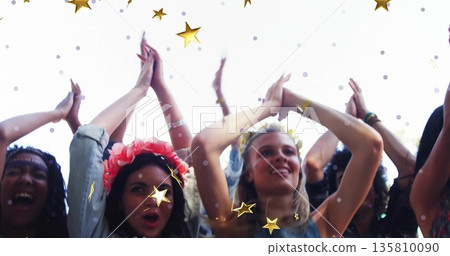 Clapping attendees raising arms at festival stage, with flower crowns, bracelets and star graphics 135810090