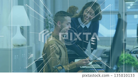 Reviewing printed report coworkers in business casual attire at office desk, with monitor and plant Reviewing printed report coworkers in business casual attire at office desk, with monitor and plant 135810133