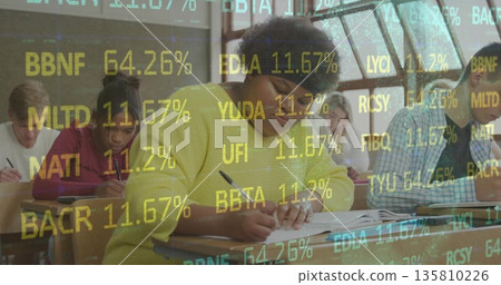 Leaning student wearing yellow sweater writing exam in classroom at desk, with floating codes Leaning student wearing yellow sweater writing exam in classroom at desk, with floating codes 135810226