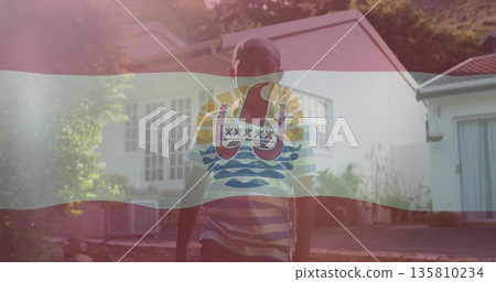 Standing boy wearing striped shirt and shorts on front yard paved path, with flag overlay Standing boy wearing striped shirt and shorts on front yard paved path, with flag overlay 135810234