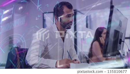 Middle Eastern IT specialist taking notes on notepad at open-plan office, with shirt and headset Middle Eastern IT specialist taking notes on notepad at open-plan office, with shirt and headset 135810677