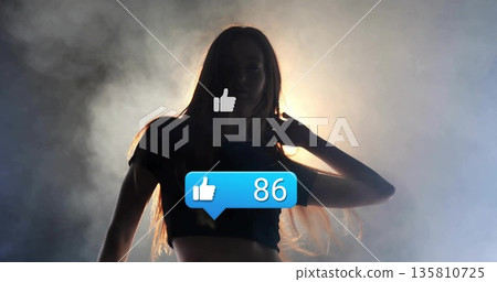 Glowing woman silhouette wearing crop-top in studio haze, thumbs-up icon and like bubble showing 86 Glowing woman silhouette wearing crop-top in studio haze, thumbs-up icon and like bubble showing 86 135810725