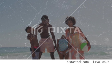 Smiling family in swimwear playing in shallow surf at sunlit beach, with inflatable beach ball Smiling family in swimwear playing in shallow surf at sunlit beach, with inflatable beach ball 135810806