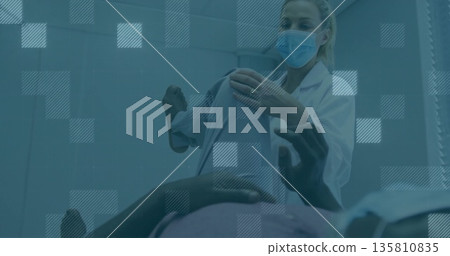 Masked clinician lifting patient's leg assessing joint mobility in exam room, with coat, copy space Masked clinician lifting patient's leg assessing joint mobility in exam room, with coat, copy space 135810835