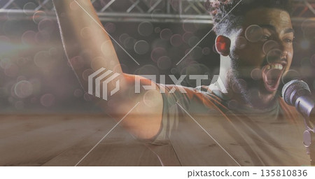 Singing adult male in t-shirt on concert stage with microphone stand and lighting truss, copy space Singing adult male in t-shirt on concert stage with microphone stand and lighting truss, copy space 135810836