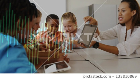 Displaying instructor holding tablet toward students at classroom table, graph overlay, copy space 135810869