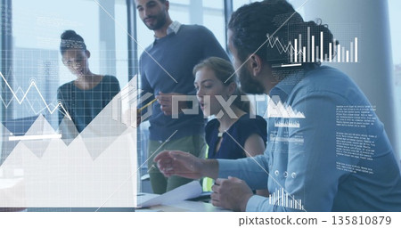 Collaborating professionals in business attire reviewing charts at white conference table in office Collaborating professionals in business attire reviewing charts at white conference table in office 135810879