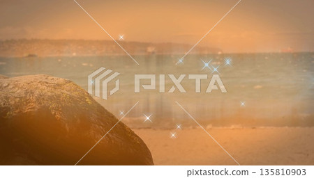 Standing mossy boulder dominating sandy beach, with ocean waves, hillside, sparkles, copy space Standing mossy boulder dominating sandy beach, with ocean waves, hillside, sparkles, copy space 135810903