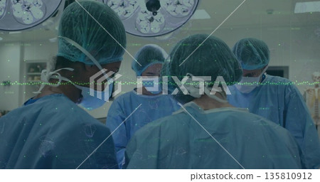 Performing surgery scrub clad team operating at OR table with overhead lights and vital monitors Performing surgery scrub clad team operating at OR table with overhead lights and vital monitors 135810912