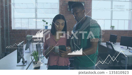 Two tech colleagues reviewing smartphone data charts in open-plan office, holding coffee mug Two tech colleagues reviewing smartphone data charts in open-plan office, holding coffee mug 135810923