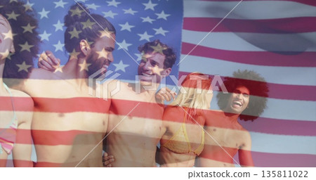 Smiling friends wearing swimwear standing close together on sunny beach, with faint US flag overlay Smiling friends wearing swimwear standing close together on sunny beach, with faint US flag overlay 135811022