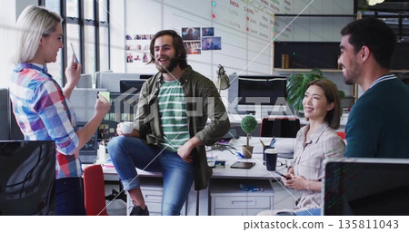 Collaborating four professionals brainstorming ideas in bright office, with smartphones and charts 135811043