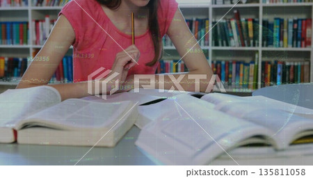 Pondering teenage girl in pink top holding pencil under chin at library table, with open textbooks Pondering teenage girl in pink top holding pencil under chin at library table, with open textbooks 135811058