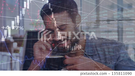 Monitoring stock chart overlays, man holding smartphone to ear and lifting coffee mug in office 135811090
