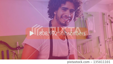 Smiling man wearing white shirt and apron, holding tool in garage with pegboard, subscriber overlay Smiling man wearing white shirt and apron, holding tool in garage with pegboard, subscriber overlay 135811101