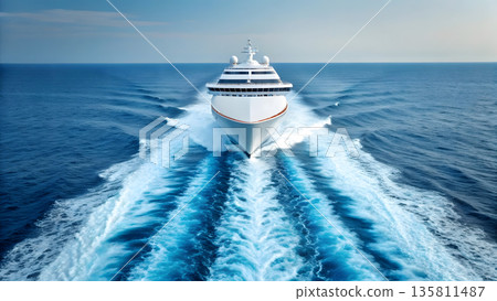 Luxury cruise ship navigating through calm ocean waters with wake trails behind 135811487