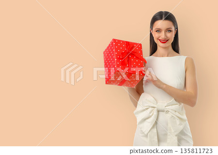 Woman presenting a red gift box with white polka dots Woman presenting a red gift box with white polka dots 135811723