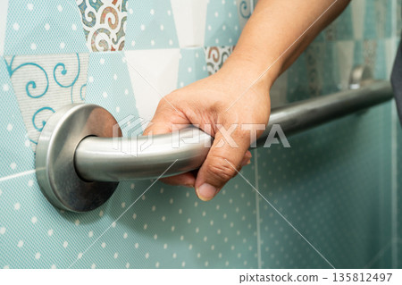 Asian woman patient use handrail safety in toilet support rail in bathroom. 135812497