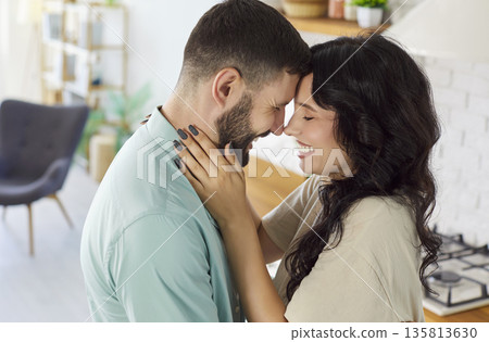 Romantic couple cuddling in bright home kitchen, sharing happiness and warm smiles Romantic couple cuddling in bright home kitchen, sharing happiness and warm smiles 135813630