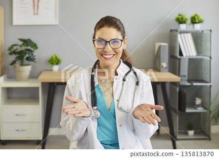 Smiling female doctor with stethoscope gesturing open hands in clinic office Smiling female doctor with stethoscope gesturing open hands in clinic office 135813870