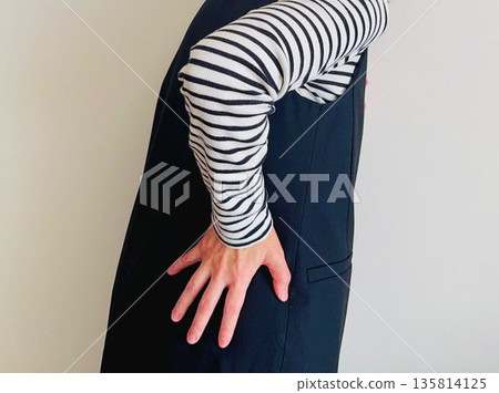 Woman putting her hands on her painful lower back 135814125