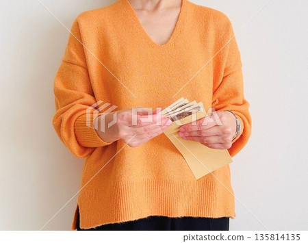 一位家庭主婦正在數棕色信封裡的錢。 一位家庭主婦正在數棕色信封裡的錢。 135814135