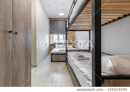 Modern hostel dormitory with industrial bunk beds and wooden wardrobe 135814509