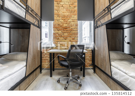 Symmetrical loft hostel interior with bunk beds and workspace 135814512
