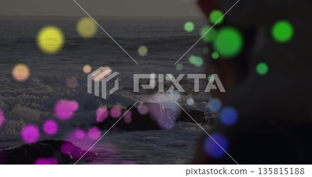 Crashing waves hitting rocks on coast at twilight with bokeh lights, shirted silhouette, copy space 135815188