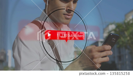 Man wearing white shirt checking subscriber overlay on city sidewalk, with smartphone earphones 135815258