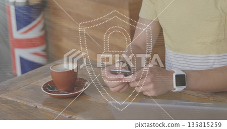 Checking smartphone in yellow tee at cafe beside UK flag cylinder with security icon, copy space Checking smartphone in yellow tee at cafe beside UK flag cylinder with security icon, copy space 135815259