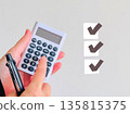 一隻手拿著計算機和一份清單 135815375