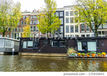 A floating house in Amsterdam canal. Boat home on water. Houseboat in Netherlands A floating house in Amsterdam canal. Boat home on water. Houseboat in Netherlands 135816641